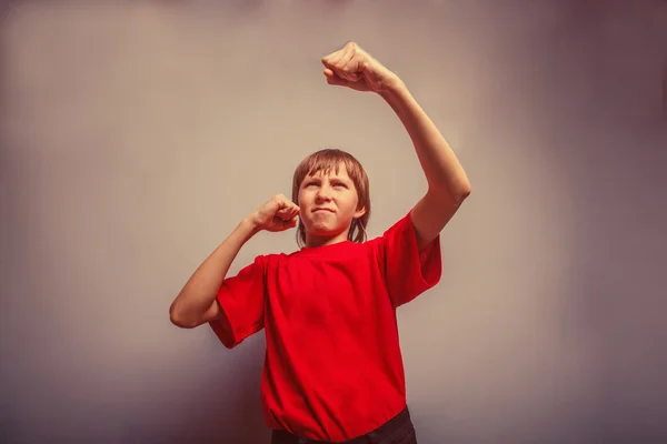 Boy, teenager, twelve years in a red shirt,  showing his fists r — ストック写真