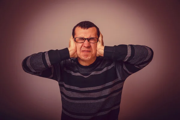 European-looking male covering his ears with his hands brunet cr — Stock Photo, Image