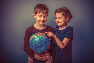Teenage boy holding a globe and smiling girl shows a finger on a