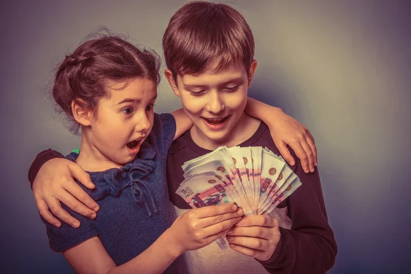 Teenage boy and girl holding money bills in his hands on a gray — Stock Photo, Image