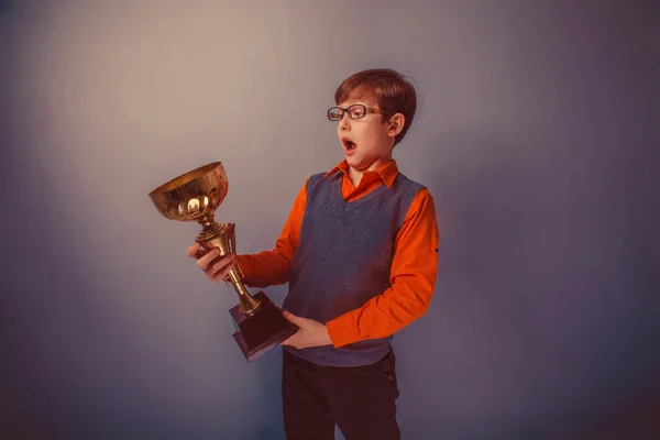 Europeu-olhando menino de dez anos de premiação copo no fundo cinza r — Fotografia de Stock