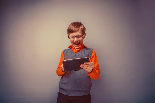 Europese uitziende jongen van tien jaar in glazen speelt tablet laughi — Stockfoto