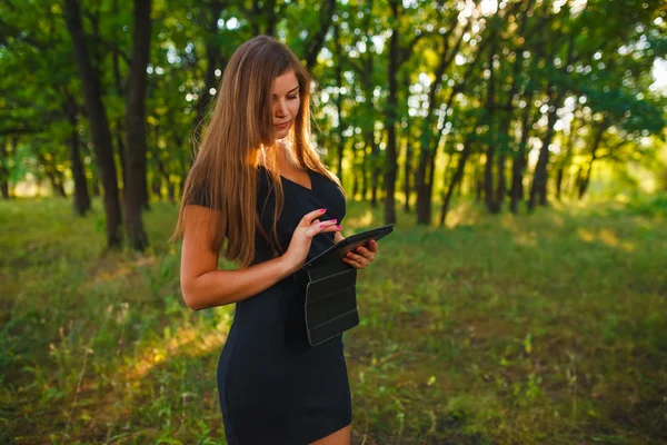 Woman girl working on a tablet in the woods on the nature of the — Stockfoto