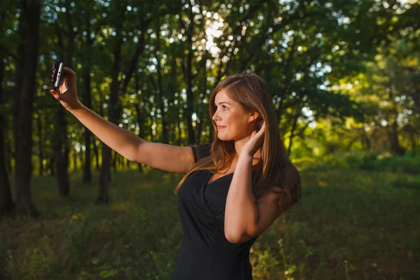 Girl woman sELF making self photo on the phone on nature green b — Stock fotografie