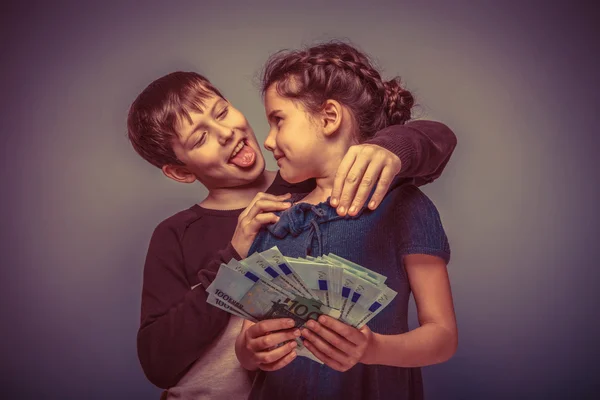 Teen dziewczyna około siedmiu lat trzyma pieniądze chłopiec teen przytulanie — Zdjęcie stockowe