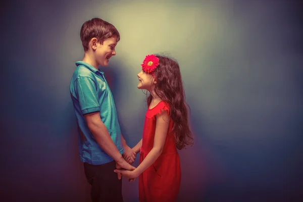 Teen girl holding hands teenage boy on gray background retro — ストック写真