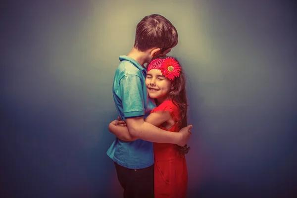 Teen girl hugging a teenage  boy on gray  background retro — ストック写真