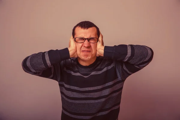 European-looking male covering his ears with his hands brunet re — Stock Photo, Image