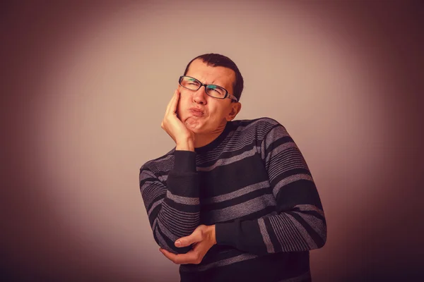 Male of European appearance brunet put his hand to his cheek on — Stock Photo, Image