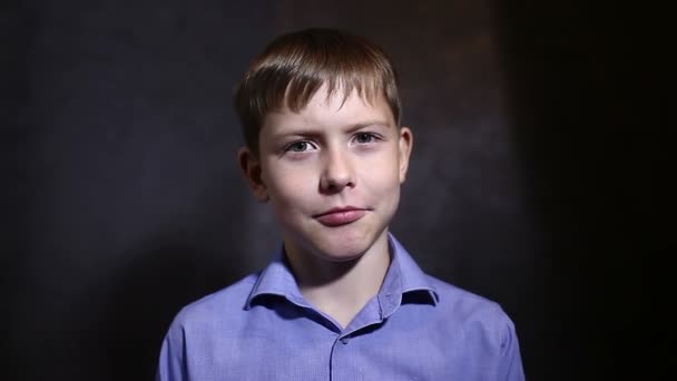 Teen boy zegt praten praten interview in blauw shirt glimlachend studio achtergrond video — Stockvideo