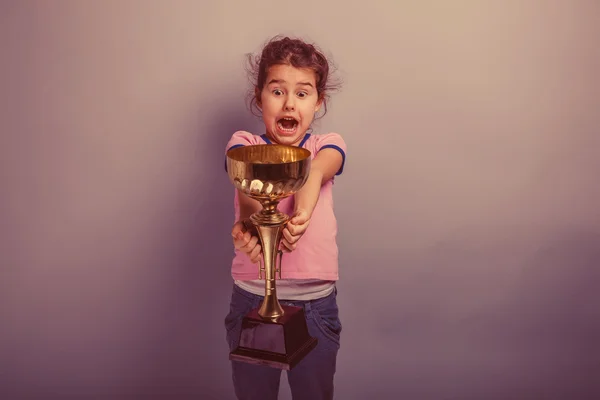 Menina criança 6 anos de aparência europeia detém uma xícara em seu han — Fotografia de Stock