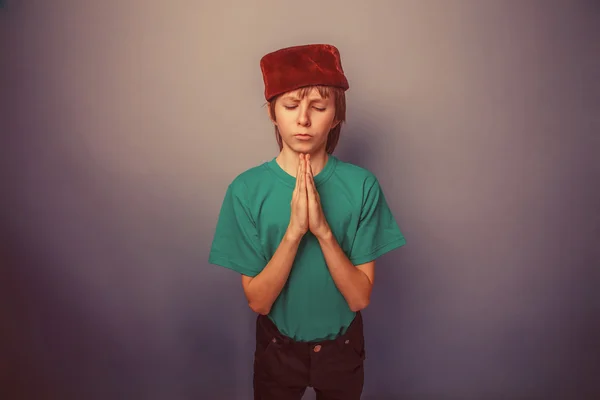 Muslimischer Junge von zehn Jahren, Schirmmütze, Gebet auf grauem Hintergrund — Stockfoto
