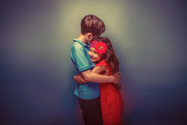 Teen girl hugging a teenage boy on a gray  background retro — Stock Photo, Image