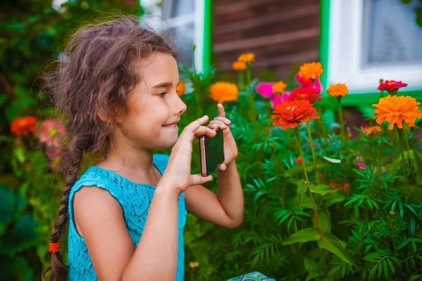 Teen girl takes pictures of the outside flowers smiling — Stock Photo, Image