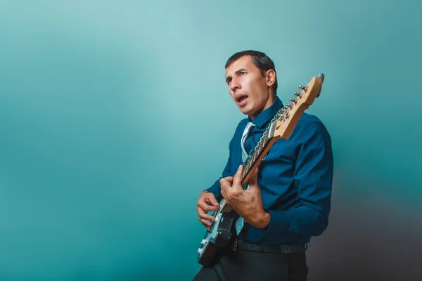 A man of European appearance thirty years of playing guitar on a — Stock Photo, Image