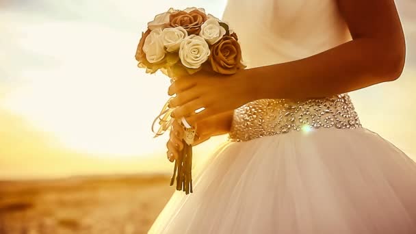 Novia boda celebra un ramo de boda primer plano grande al atardecer en la playa el sol se pone el exterior — Vídeos de Stock