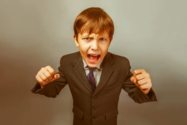 A boy of twelve European appearance in a suit shouting angry  on — Stock Photo, Image