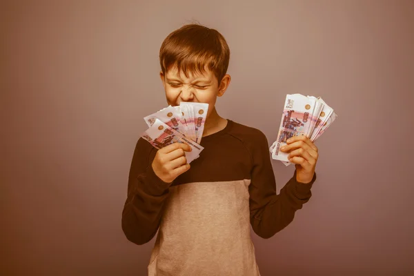 Baby boy teenager European appearance holds a brown hair bill an — Stock Photo, Image