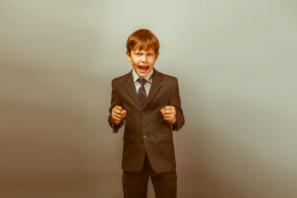 A boy of twelve European appearance in a suit shouting angry on — Stock Photo, Image