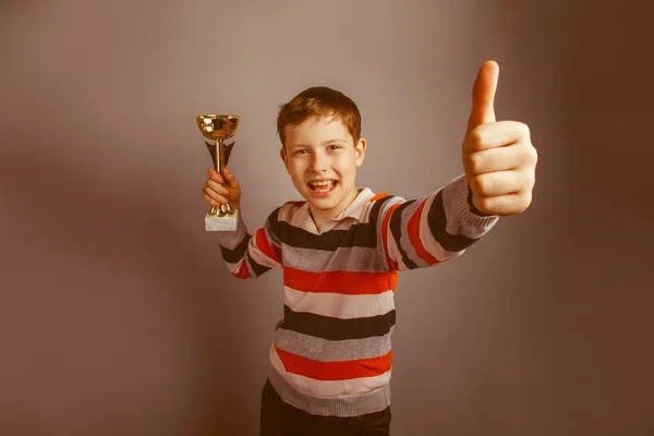 Chico de aspecto europeo de diez años sosteniendo un premio de copa pulgares hacia arriba — Foto de Stock