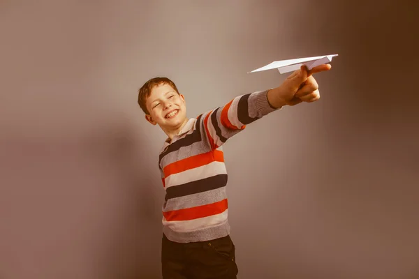 Chico de aspecto europeo de diez años jugando avión de papel en un gr —  Fotos de Stock