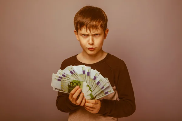 Baby boy teenager European appearance brown hair holding bills a — Stock Photo, Image