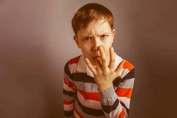 Europeo-looking ragazzo di dieci anni lecca il dito su un grigio ba — Foto Stock