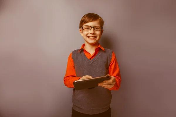 European-looking boy of ten  years in glasses holding tablet in — Stock Photo, Image