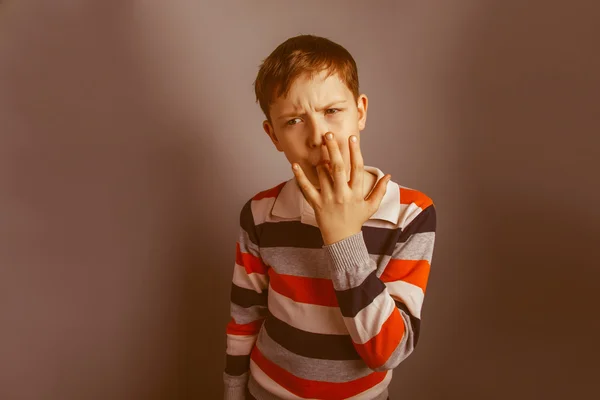 Chico de aspecto europeo de diez años lame su dedo en un bac gris — Foto de Stock