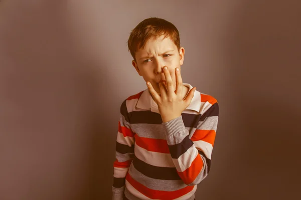 Europese uitziende jongen van tien jaar likt zijn vinger op een grijze bac — Stockfoto