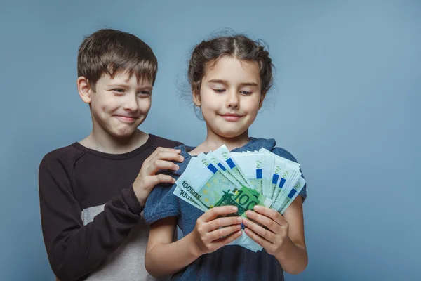 Teenage  boy and girl holding  money bills in his hands on a gra — Stock Photo, Image