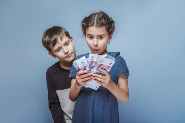 Teenage  boy and girl holding money bills in his hands on a gray — Stock Photo, Image