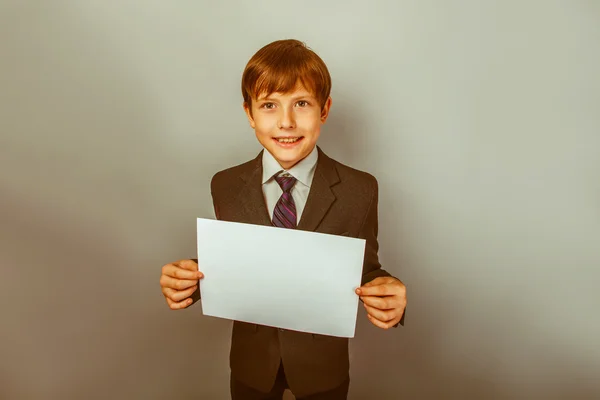 A boy of twelve European appearance in a suit holding a blank sh — Stock Photo, Image