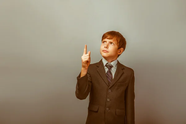 A boy of twelve European appearance in a suit shows his finger t — Stock Photo, Image