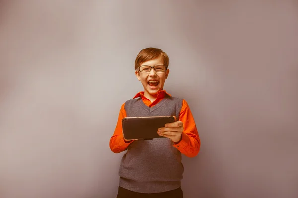 European -looking  boy of ten years in glasses holding tablet in — Stock Photo, Image