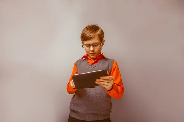 European-looking  boy of ten years in glasses holding tablet in — Stock Photo, Image