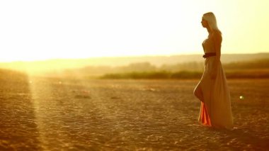 seksi genç baştan çıkarıcı portre kız Kadın elbisesi günbatımı sarı çölde kum yavaş yavaş yürüme geliştirir