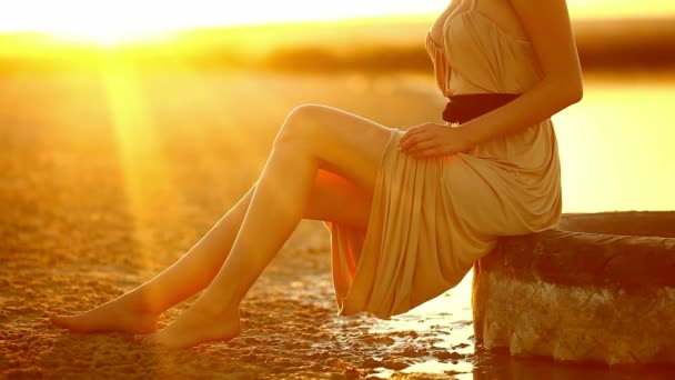 年轻的女孩坐在一个女人穿过沙漠的沙子海滩，在日落性感黄色沙漠车轮胎大弯曲腿上 — 图库视频影像
