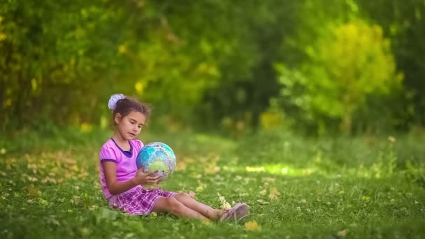 Έφηβος κορίτσι, συνεδρίαση για την πράσινη χλόη, παίζοντας μελετώντας Globe ευτυχισμένη χρώμα — Αρχείο Βίντεο