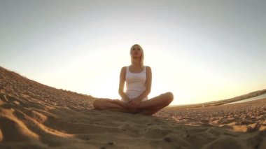 Beyaz yoga sağlıklı yaşam meditasyon çölde kum üzerinde oturan sarışın kadın giyinmiş