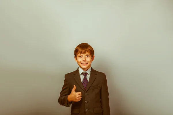 Мальчик двенадцати лет европейского происхождения в костюме паказывет большие пальцы — стоковое фото