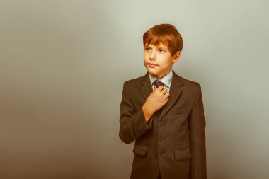 a boy of twelve European appearance in a suit straightens his ti