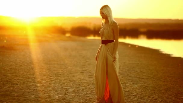 젊은 매혹적인 섹시 한 여자 여자 드레스 개발 일몰 노란 사막 모래 노란색 배경 미소에 서 — 비디오