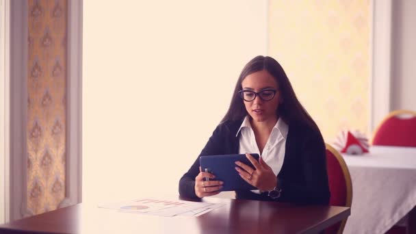 Muchacha joven en gafas hombre de negocios corriendo trabajo distante en la tableta en la mesa documentos gráficos freelance mujer freelance — Vídeo de stock