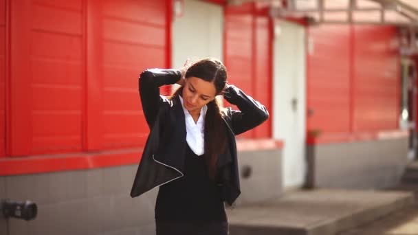 Fille debout sur la rue dans la ville se développe vent derrière les cheveux de la femme fond rouge — Video