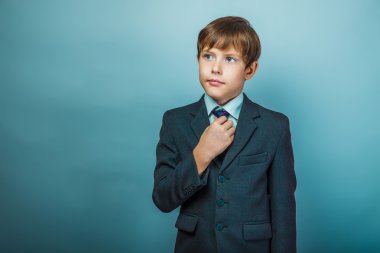 European appearance teenager boy in a business suit straightens