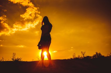 European appearance young woman standing at sunset looking at th