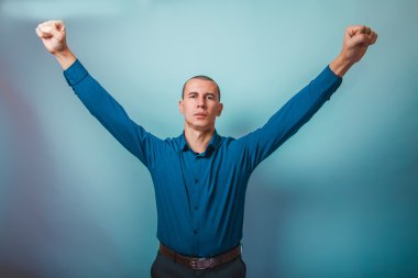 a man in a blue shirt European appearance raised his hands up ag