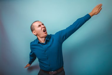 a man in a blue shirt European appearance spread his arms in a p