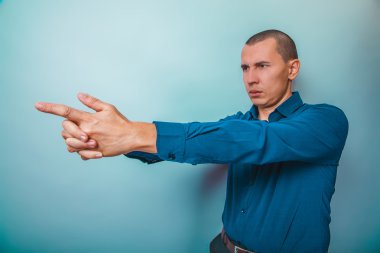a man in a blue shirt European appearance shows hands a gun taki